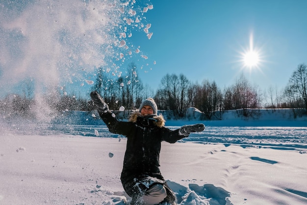 Een vrouw gooit sneeuw in de lucht tegen de zon