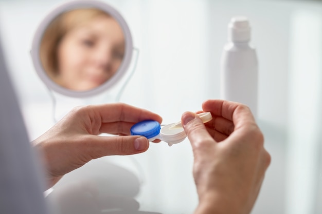 Een vrouw haalt een contactlens uit een container met een pincet