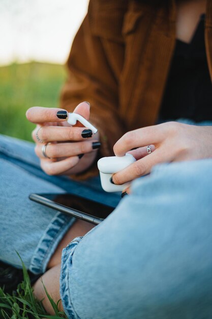 Een vrouw haalt witte draadloze oordopjes uit de oplaaddoos om naar muziek te luisteren