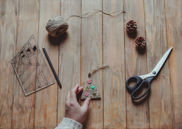 Een vrouw heeft een handgemaakt kerstboomspeelgoed in haar hand. Concept van Kerstmis diy. Bovenaanzicht