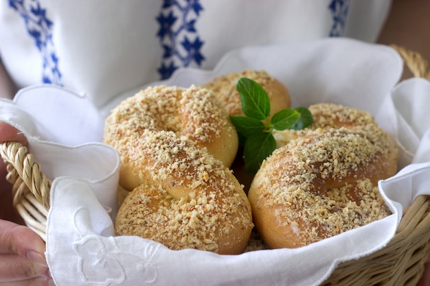 Een vrouw heeft een mand met traditionele Roemeense en Moldavische zoete broodjes in de vorm van een acht met nootkruimels.