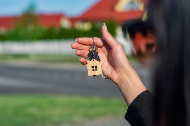 Een vrouw houdt de sleutels van het huis in haar handen tegen de achtergrond van woongebouwen concept voor het kopen en huren van appartementen