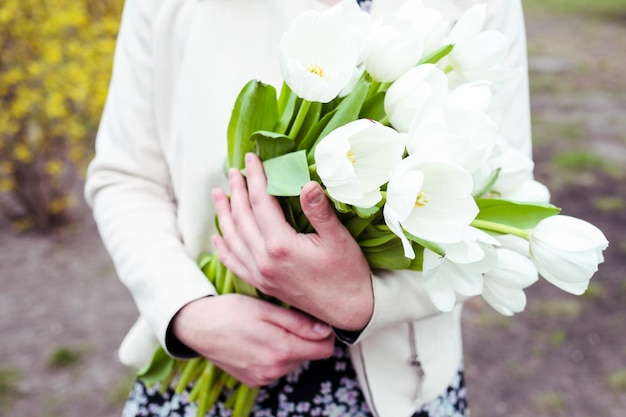 Een vrouw houdt een boeket bloemen in haar handen.