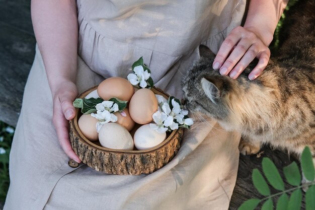 Een vrouw houdt een houten bord met paaseieren vast en streelt een kat Pasen in rustieke stijl