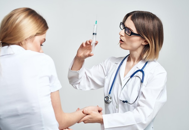 Een vrouw houdt een injectiespuit in haar hand en een vrouwelijke patiënt in een wit t-shirt is een bang model