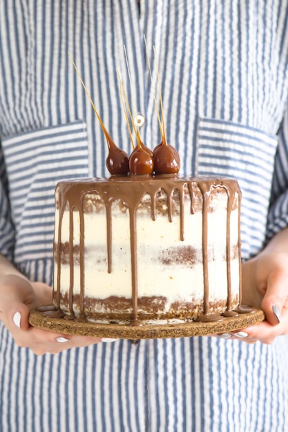 Een vrouw houdt een kleine ronde mooie cake gevuld met chocolade