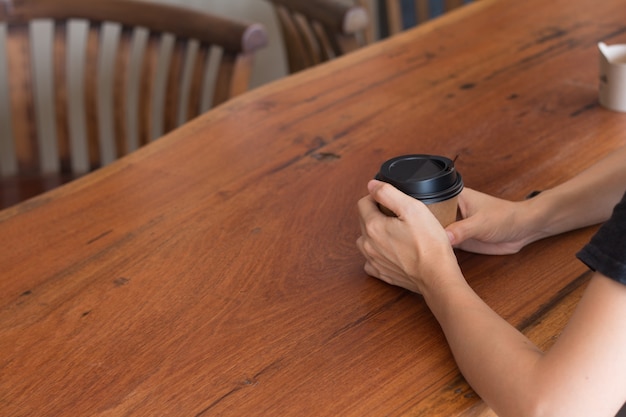 Een vrouw houdt een koffiekop in koffiewinkel bij middag.