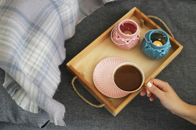 Een vrouw houdt een kop koffie en melk op een houten dienblad