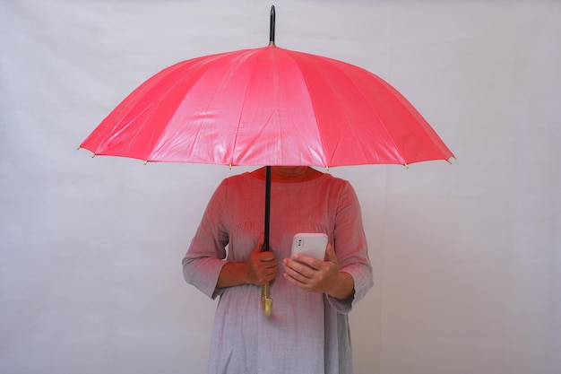 Een vrouw houdt een mobiele telefoon onder een rode paraplu