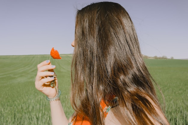 Een vrouw houdt een papaverbloem vast in een veld