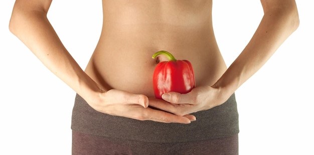 Een vrouw houdt een rode paprika in haar handen bij haar buik. Het concept van gezond eten.
