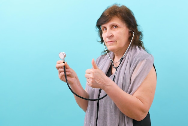 Een vrouw houdt een stethoscoop vast en toont een duim omhoog op een blauwe achtergrond Vrolijke hulp Klinische consultatie Diagnose Ziekteonderzoek Onderzoek Expertise Vriendelijke Gezondheidszorg Houd