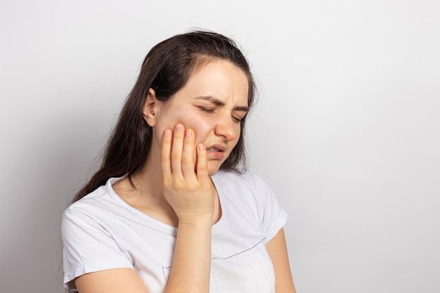 Een vrouw houdt een zere tand vast met haar hand