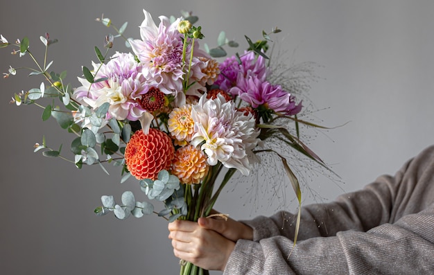 Een vrouw houdt in haar hand een feestelijk bloemstuk met heldere chrysantenbloemen, een feestelijk boeket.