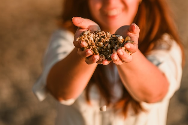 Een vrouw houdt prachtige kiezelstenen van het strand in haar handen