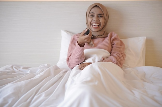 Een vrouw in bed met een afstandsbediening in haar hand