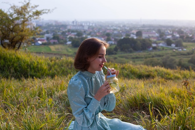 Een vrouw in blauwe jurk zit op een picknick in een park met panoramisch uitzicht