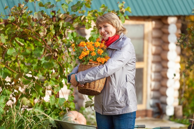 Een vrouw in de herfsttuin oogst en verwijdert afval.