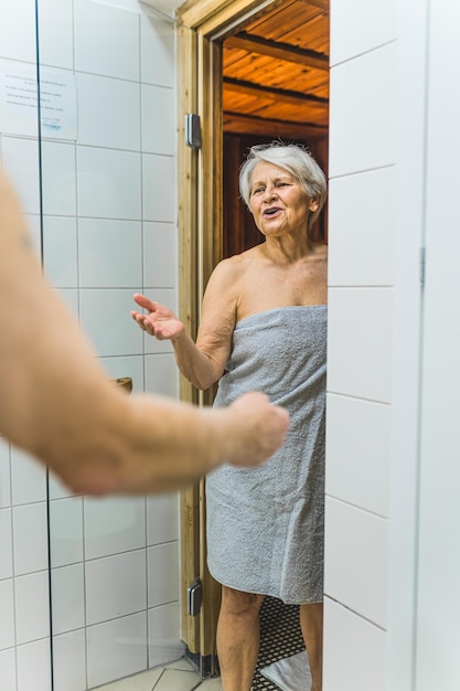 Foto een vrouw in een badjas staat in een douche en praat met haar man.