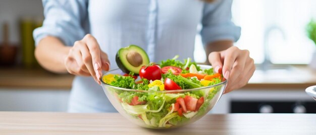 een vrouw in een blauw shirt houdt een kom salade vast