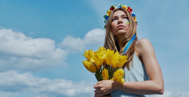 een vrouw in een blauwe en witte jurk houdt een boeket gele tulpen vast