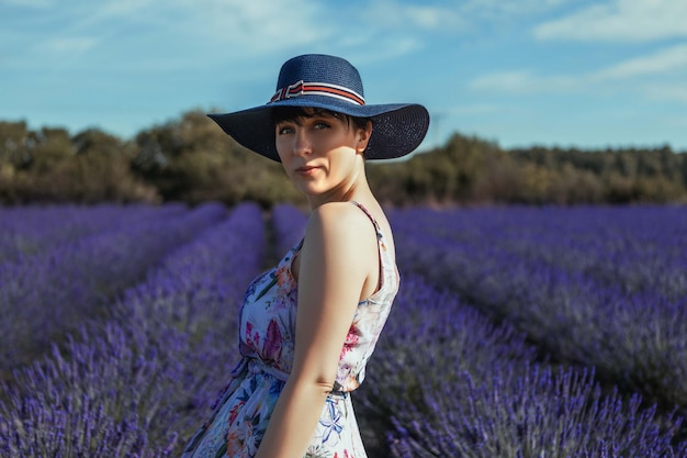 Een vrouw in een blauwe jurk staat in een lavendelveld