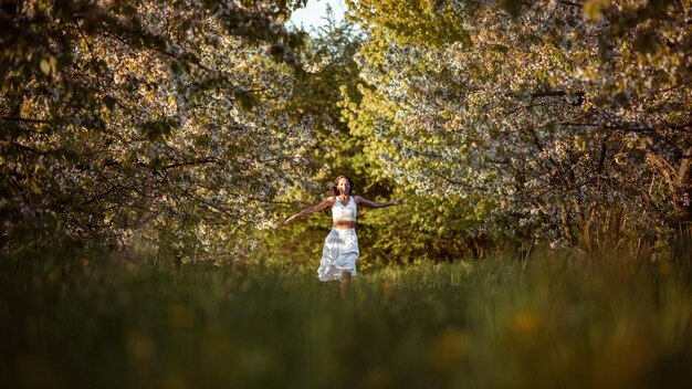 Een vrouw in een bloemenveld met uitgestrekte armen