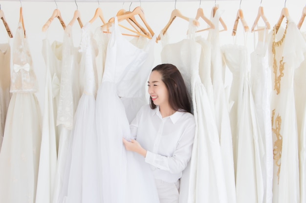 Een vrouw in een bruidsjurkenwinkel lacht terwijl ze haar trouwjurk vasthoudt.