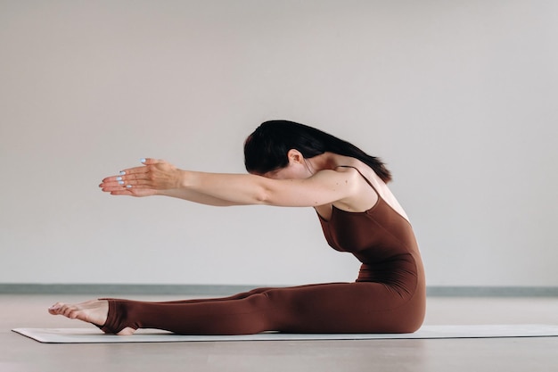 Een vrouw in een bruin pak doet yoga in een fitnessruimte Gezonde levensstijl fitnesstraining zelfzorg