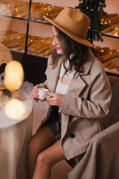 Een vrouw in een coffeeshop drinkt koffie of thee Kerstmis en Nieuwjaar concept