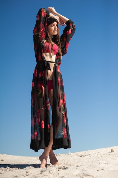 Een vrouw in een gebloemde kimono staat op een heuvel met de lucht achter zich.