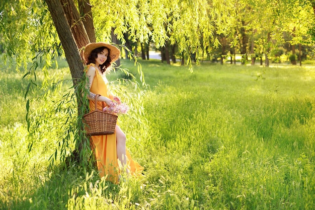 Een vrouw in een gele jurk en een strohoed in de tuin in de zomer op een wandeling banner