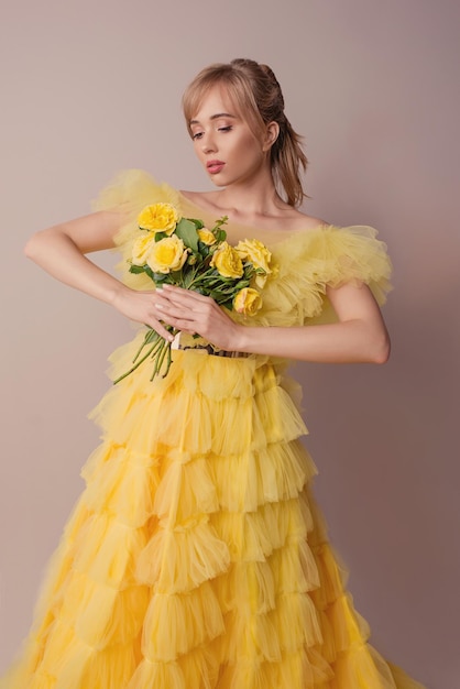 Een vrouw in een gele jurk houdt een boeket bloemen vast.
