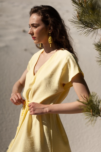 Een vrouw in een gele jurk staat in de woestijn.