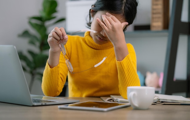 Foto een vrouw in een gele trui zit aan een bureau met een laptop en een tablet