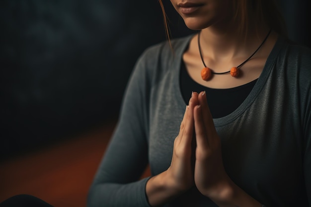 Een vrouw in een grijs shirt doet een yogahouding met haar handen in elkaar.