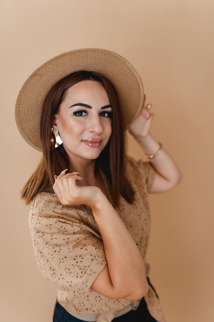 een vrouw in een hoedenshirt met poseren op een beige achtergrond