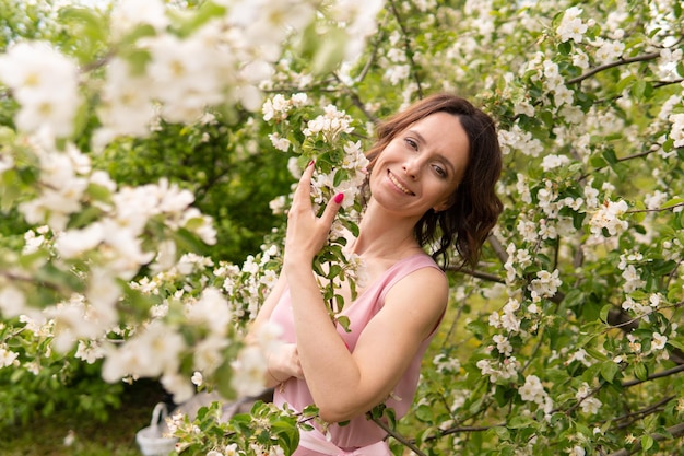 Een vrouw in een jurk in de buurt van een bloeiende lenteboom. Romantische gelukkige stemming.