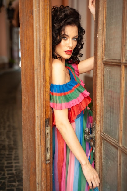 Een vrouw in een kleurrijke jurk staat in een deuropening.