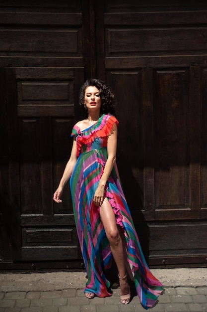 Een vrouw in een kleurrijke jurk staat voor een deur