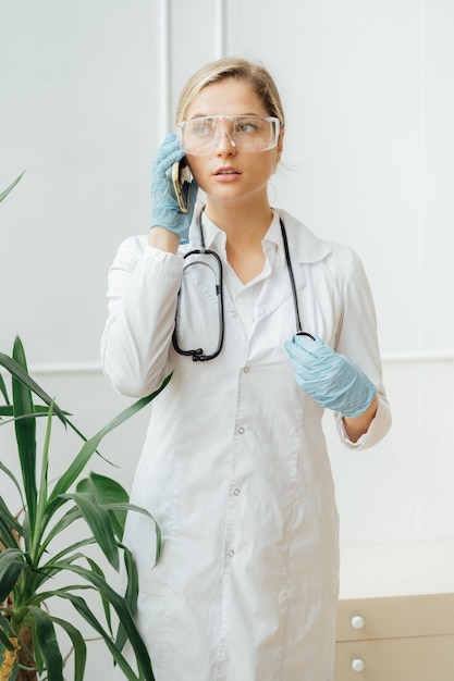 Een vrouw in een laboratoriumjas telefoneert.