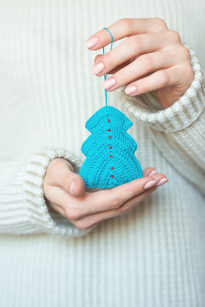 Een vrouw in een lichte warme wollen trui met een speeltje in haar handen, kopieer ruimte, selectieve focus