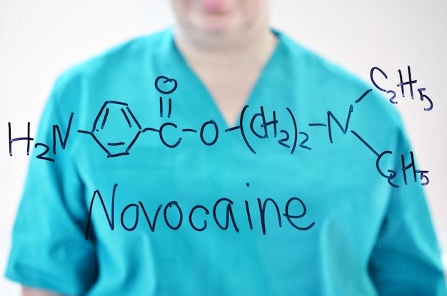Foto een vrouw in een medisch uniform schrijft chemische formule novocaine met stift op een glas