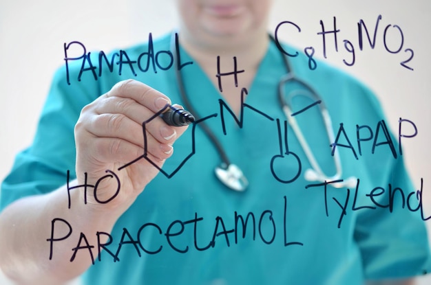 Foto een vrouw in een medisch uniform schrijft chemische formule paracetamol met stift op een glas