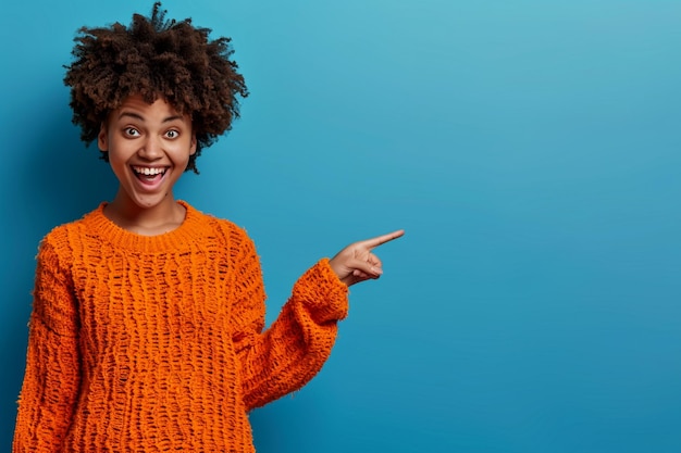 een vrouw in een oranje trui die naar rechts wijst met haar vinger naar boven