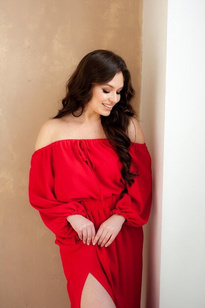 Een vrouw in een rode jurk staat voor een muur