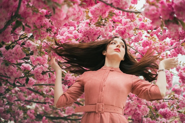 Een vrouw in een roze jurk wordt omringd door roze bloemen.