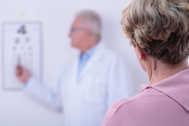 Foto een vrouw in een roze overhemd staat voor het whiteboard van een arts.