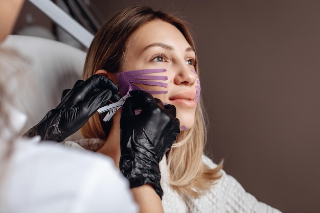 Een vrouw in een schoonheidssalon krijgt een procedure voor verjonging en verbetering van de huid van het gezicht met tapes