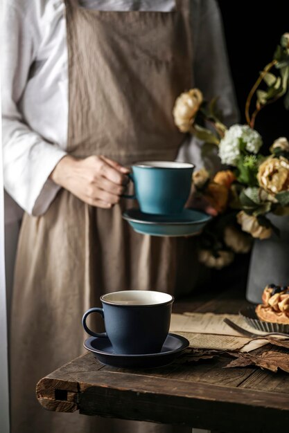 Een vrouw in een schort houdt een kopje koffie en geniet van een rustig moment met koffie